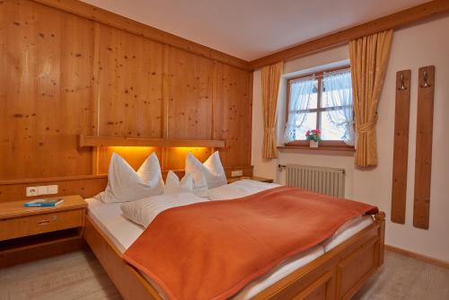a bedroom with a bed with an orange blanket on it at Landhaus Franziskus in Reit im Winkl