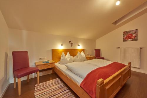 a bedroom with a large bed and two chairs at Landhaus Franziskus in Reit im Winkl