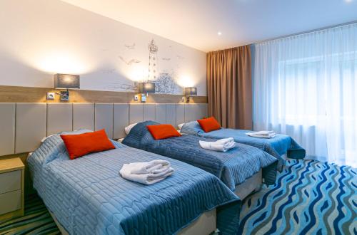 two beds in a hotel room with towels on them at Bagińscy Spa in Pobierowo