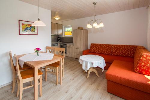 a living room with a red couch and a table at Ferienwohnung Plenk inkl. Chiemgaukarte in Ruhpolding