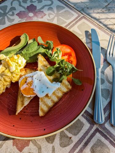 a plate of eggs and toast with tomatoes and greens at Relais Terre di Romanello in Noto