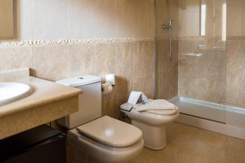 a bathroom with a toilet and a sink and a shower at Pensión Capitan in Aldán