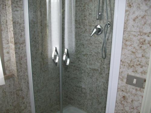 um chuveiro com uma porta de vidro e uma cabeça de chuveiro em Hotel Santorotto em Sinalunga