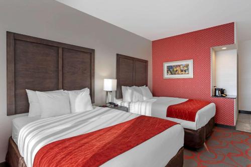 two beds in a hotel room with red walls at Comfort Inn & Suites near Stadium in Bronx