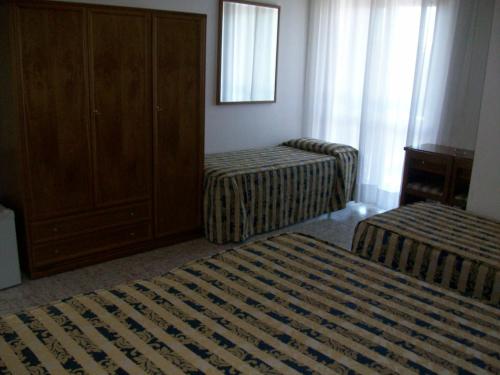 a room with two beds and a dresser and a bedroom at HOTEL SANTOROTTO di FABIO TERROSI in Sinalunga