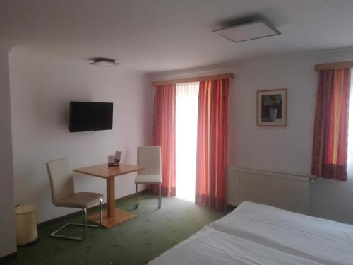 a room with a bed and a table and a television at Haslgut in Fuschl am See