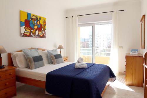 1 dormitorio con 1 cama con manta azul en Rocha Beach Flat by ALgest, en Portimão