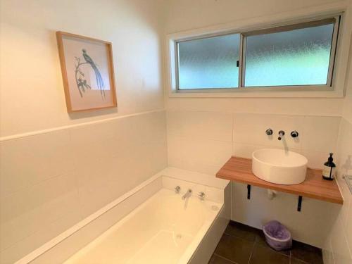 a bathroom with a tub and a sink and a window at Apollo bay Holiday House in Apollo Bay