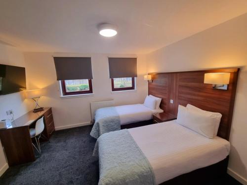 a hotel room with two beds and a desk at Premier Lodge in Falkirk