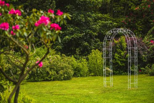 a metal arch in a yard with pink flowers at Hotel SEN in Senohraby