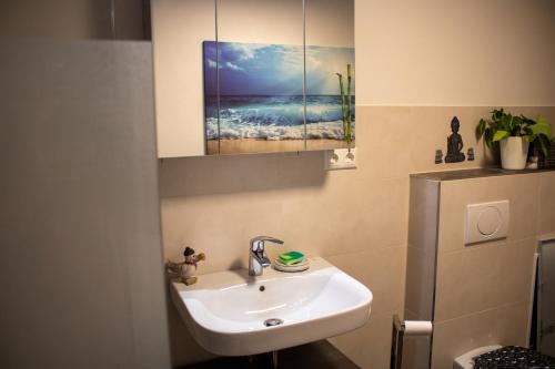 een badkamer met een wastafel en een foto van de oceaan bij Altstadtidyll 50qm - Terrace - Central - Washer in Haldensleben