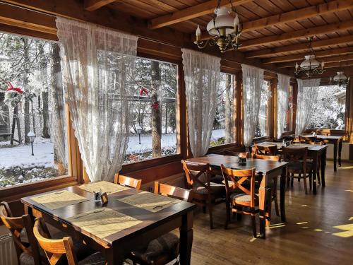 a dining room with tables and chairs and windows at Czarny Potok Wellness & Spa Zakopane Centrum in Zakopane