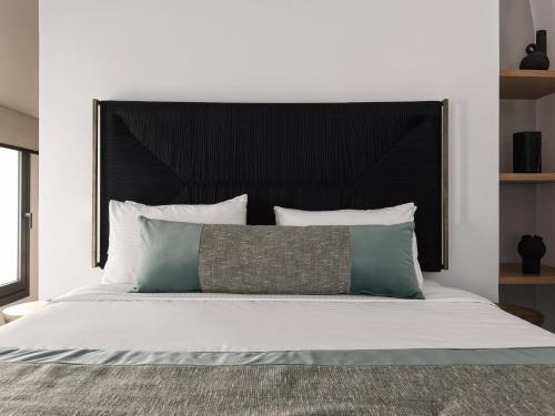 a bed with a black headboard and some pillows at La Maltese Estate in Imerovigli