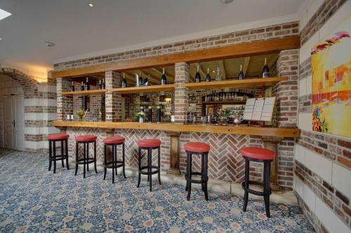 a bar with red stools in a room at Hôtel de L'univers in Arras