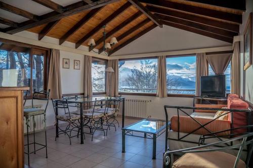 uma sala de estar com mesas, cadeiras e janelas em Utaka Cabañas y Apartamentos em Ushuaia