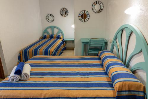 two beds in a room with clocks on the wall at Casa Juanita in Peñíscola