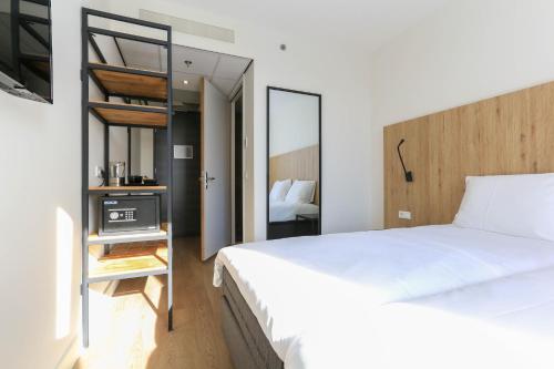 a bedroom with a large white bed and a mirror at Fletcher Hotel Rotterdam-Airport in Rotterdam