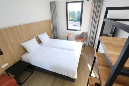 a bedroom with a bed with white sheets and a window at Fletcher Hotel Rotterdam-Airport in Rotterdam