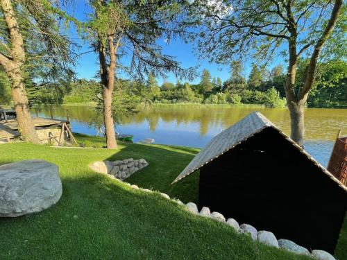 a doghouse in the grass next to a lake at Hyggelig sommerhus. med udsigt, til vand fra senge in Veksø