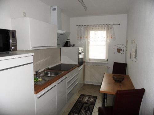 a kitchen with white cabinets and a table and a window at Gartenhaus Diana - 120 m zum Strand in Bansin