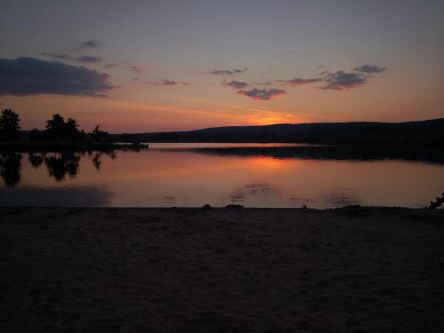 a sunset over a lake with the sun setting at Ferienhaus Traumblick direkt am See in Weißenstadt