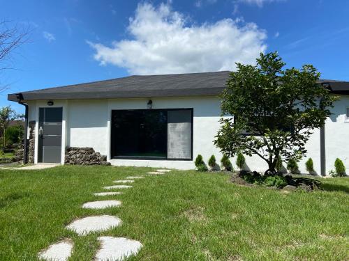 a house with a lawn with stepping stones in front of it at Jeju Time in Jeju