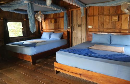 two beds in a room with wooden walls at Lazy Beach in Koh Rong Sanloem