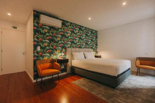 a hotel room with a bed and two chairs at Azores Inn - Family Suites in Ponta Delgada