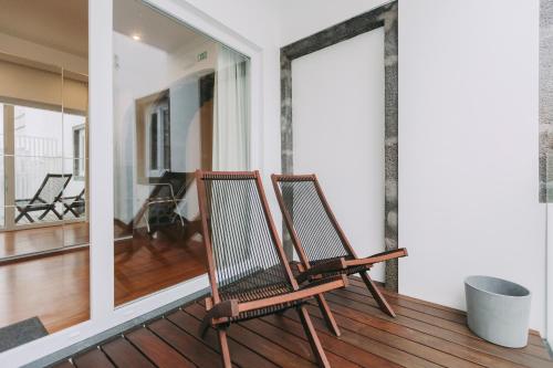 two chairs sitting on a porch with a balcony at Azores Inn - Family Suites in Ponta Delgada
