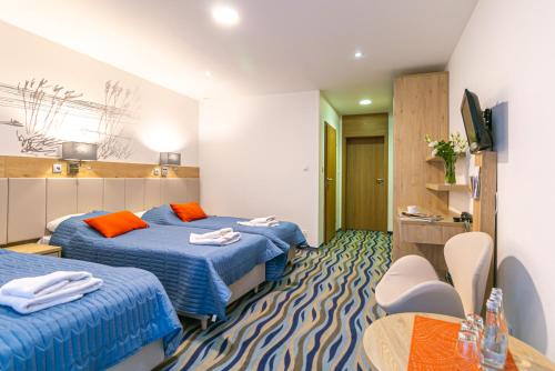 a hotel room with two beds and a table at Bagińscy Spa in Pobierowo