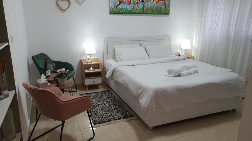 1 dormitorio con 1 cama blanca y 1 silla en B resort דירת נופש בדרום רמת הגולן, en Giv'at Yo'av
