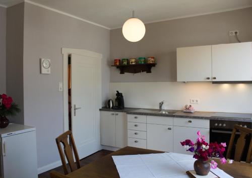 a kitchen with white cabinets and a table with flowers at Ferienwohnung Reinette in Lippoldsberg