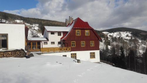 a house with a red roof in the snow at Pension Paulů in Pec pod Sněžkou
