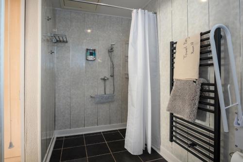 a shower with a shower curtain in a bathroom at Estuary Lodge Motel B&B in Talsarnau