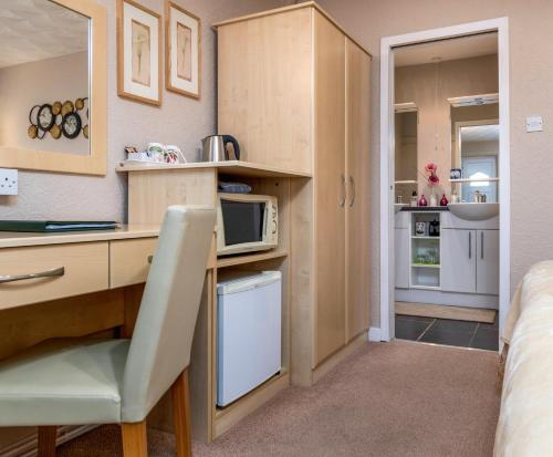 a kitchen with a desk and a microwave at Estuary Lodge Motel B&B in Talsarnau