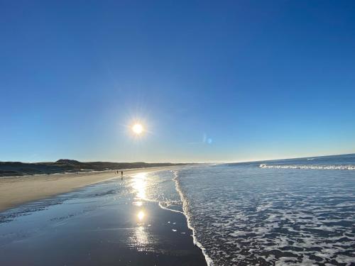 a beach with the sun shining on the water at Ferienhaus am Meer mit Kamin & Sauna - Seestern 251 in Julianadorp