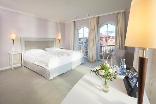 une chambre d'hôtel avec un lit et une table avec un vase de fleurs dans l'établissement Kino-Hotel Meyer, à Harsefeld