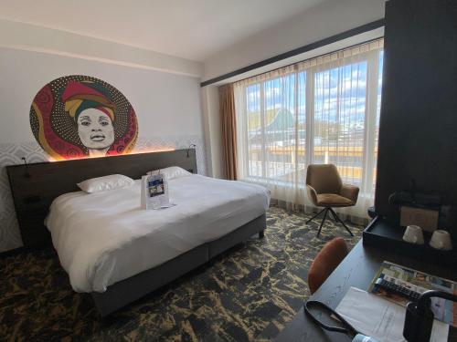 Habitación de hotel con cama extragrande y pintura en la pared en Fletcher Hotel-Restaurant ByZoo Emmen, en Emmen