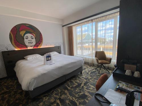 a hotel room with a king sized bed with a painting on the wall at Fletcher Hotel-Restaurant ByZoo Emmen in Emmen