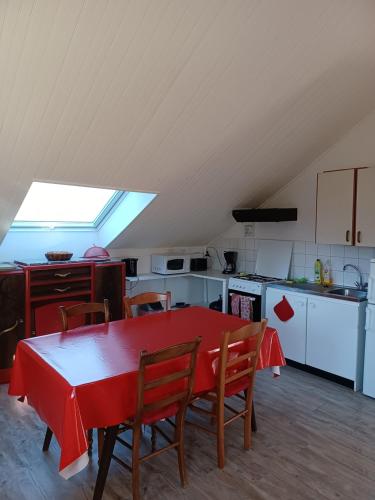 cocina con mesa roja y sillas en una habitación en appartement dans maison, calme assuré, en Corancy