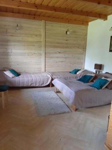 a room with three beds and a wooden wall at domek w Krynicy Zdroju in Krynica Zdrój