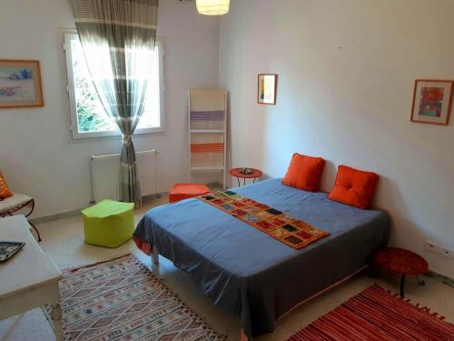 Perle de Gammarth في قمرت: غرفة نوم مع سرير مع وسائد برتقالية ونافذة