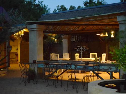 - une table et des chaises sur la terrasse la nuit dans l'établissement Little Eden Guest Lodge, à Vanderbijlpark