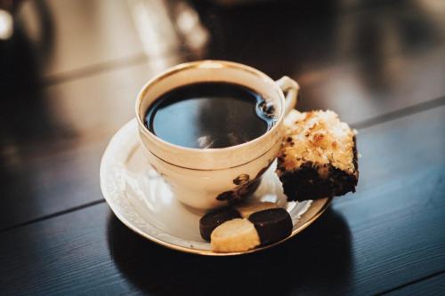 a cup of coffee and a piece of cake on a plate at Karlsberg Gård B&B in Tvååker