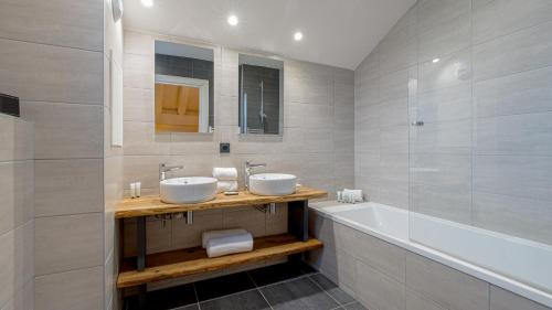 Un baño con dos lavabos y una bañera. en Chalet Juliette by Les Etincelles, en Belle Plagne