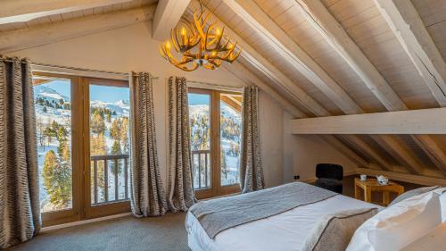 Un dormitorio con una cama y una ventana grande. en Chalet Juliette by Les Etincelles, en Belle Plagne