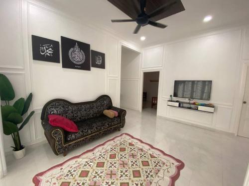 a living room with a couch and a tv at ADDA Guest House in Kota Bharu