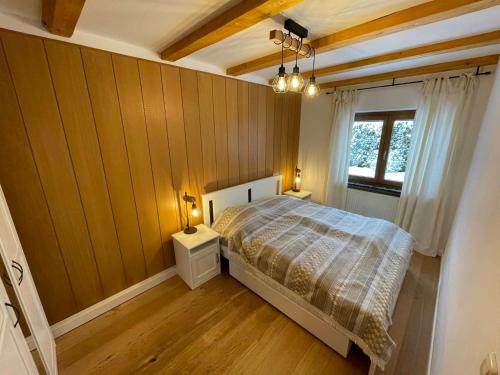 um quarto com uma cama com paredes de madeira e uma janela em Ferienhaus Marchhäuser 12 em Haidmühle