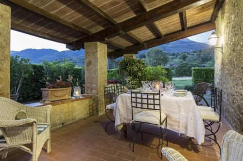a dining room with a table and chairs on a patio at Le Bicocche Farmhouse: Country Stone Villa with Pool in Camaiore between Lucca & Beaches of Versilia in Montemagno