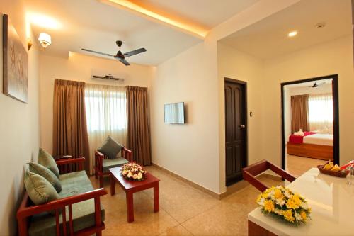 a living room with a couch and a room with a bed at Hotel Thamburu International in Trivandrum